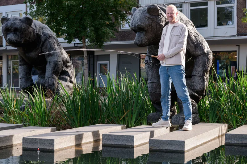 Ton Heerze met een hengel bij de beren op de markt in Hengelo
