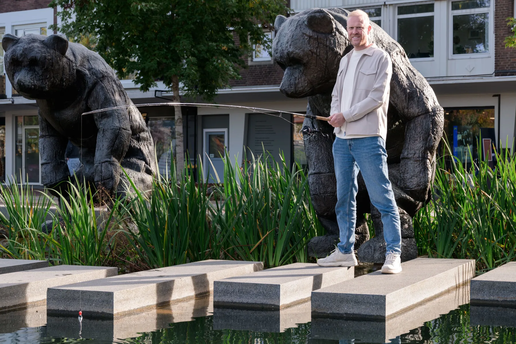 Ton Heerze met een hengel bij de beren op de markt in Hengelo